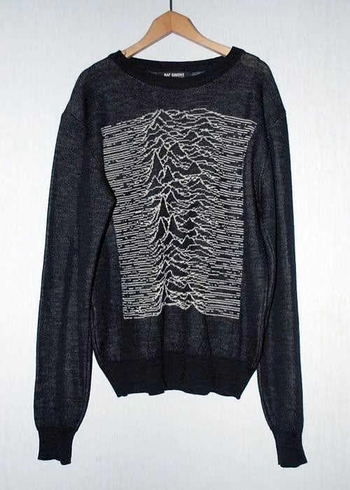 A black Raf Simons sweater on a wooden hanger with white pulse lines knitted across the front