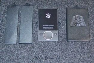 An unboxed Joy Division Zune music player and its black case, which carries a raised version of the pulse graphic